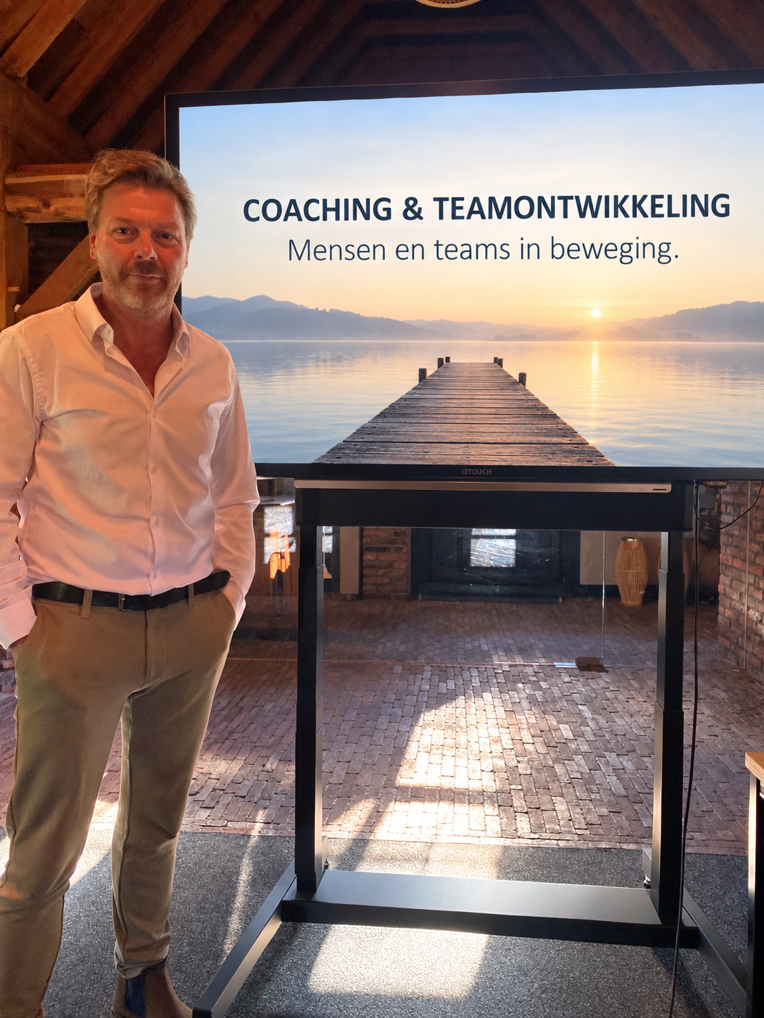Tonny bij een scherm met de tekst ‘Coaching & teamontwikkeling’